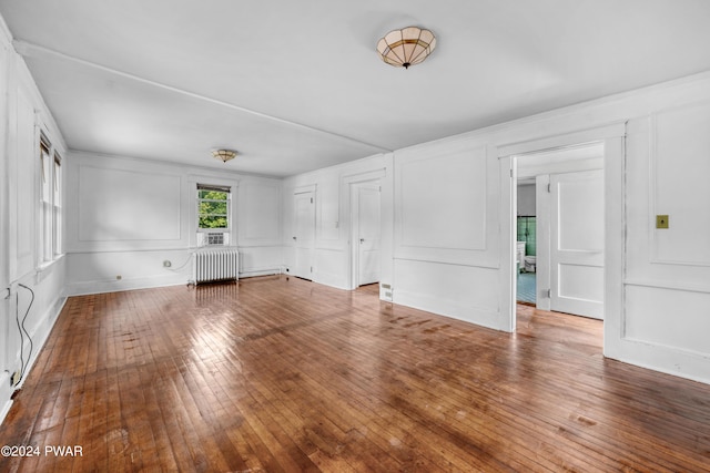 unfurnished living room featuring radiator heating unit and hardwood / wood-style flooring