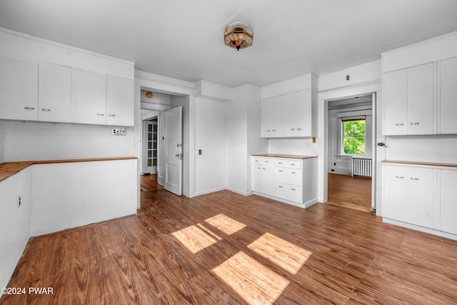 kitchen with white cabinets, radiator heating unit, and light hardwood / wood-style flooring