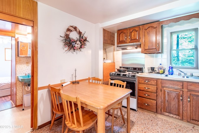 114 Springbrook Ln, Greentown, PA 18426 - kitchen featuring gas range, under cabinet range hood, brown cabinetry, light countertops, and backsplash