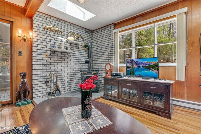 111 N Redwood Dr, Greentown, PA 18426 - interior space featuring a wood stove, a textured ceiling, a skylight, brick wall, and wood finished floors