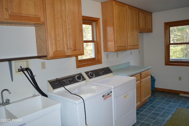 clothes washing area featuring visible vents, baseboards, washing machine and dryer, cabinet space, and a sink