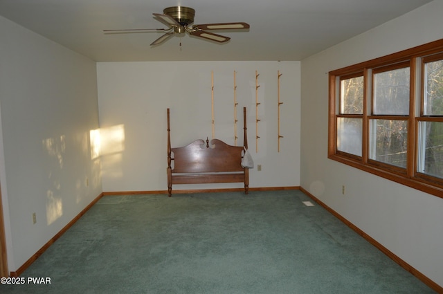 carpeted spare room featuring a ceiling fan and baseboards