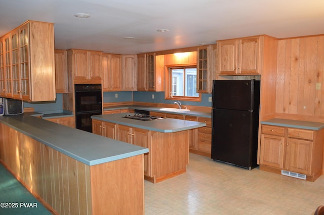 kitchen with a sink, visible vents, light floors, and black appliances