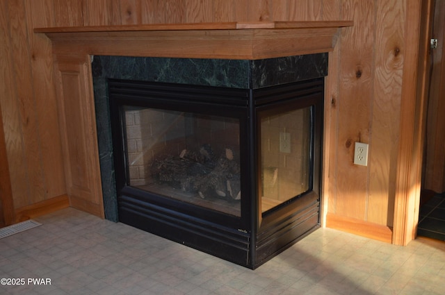 room details featuring tile patterned floors, wood walls, and a premium fireplace