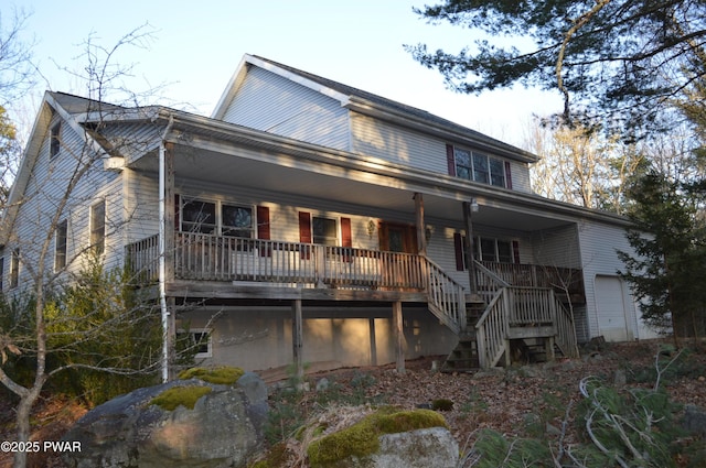 back of house with stairway, a porch, and a garage