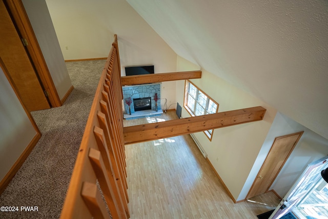 interior space with a stone fireplace, lofted ceiling, and light carpet