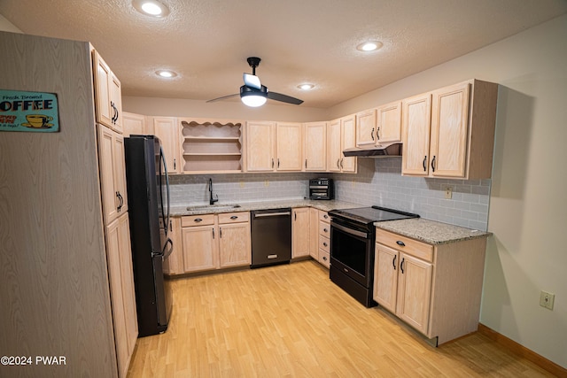 kitchen featuring black appliances, sink, light stone countertops, light brown cabinetry, and light hardwood / wood-style floors