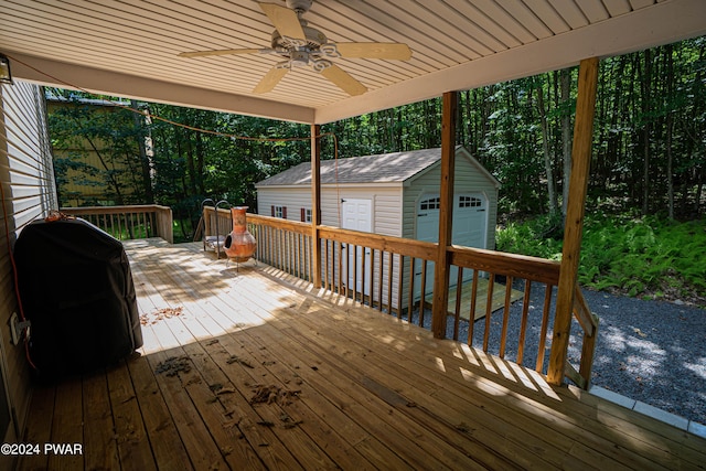 wooden terrace with area for grilling, ceiling fan, an outbuilding, and a garage