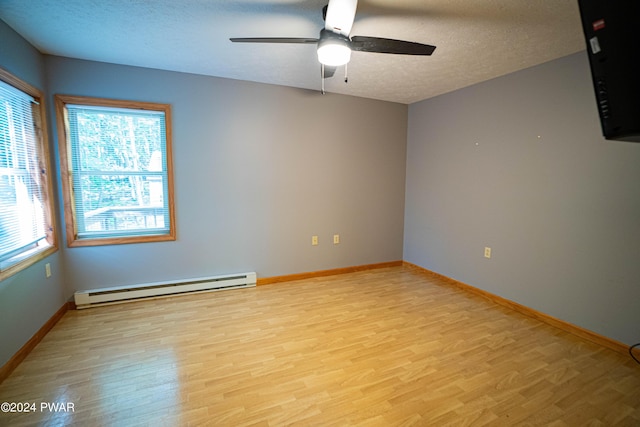 spare room with a textured ceiling, light wood-type flooring, ceiling fan, and a baseboard heating unit