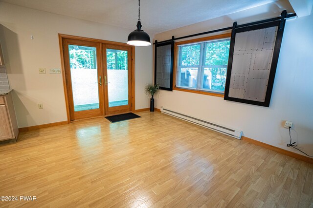 unfurnished room featuring french doors, a barn door, light hardwood / wood-style flooring, and baseboard heating