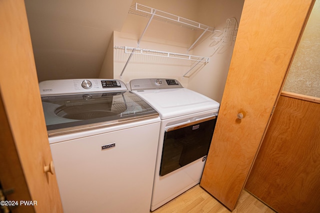 laundry room featuring washing machine and dryer, wooden walls, and light hardwood / wood-style flooring