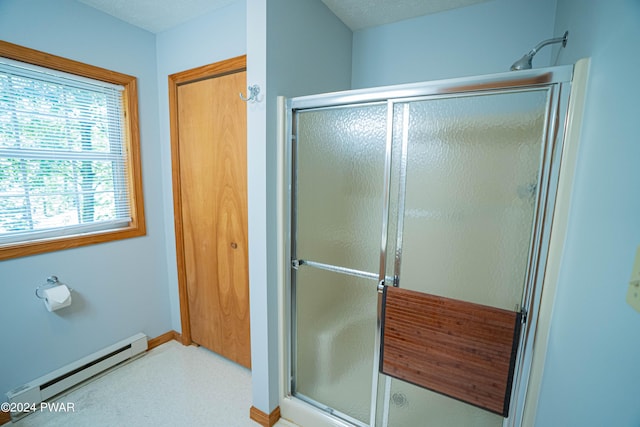 bathroom featuring a shower with shower door and a baseboard heating unit