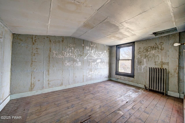 spare room with vaulted ceiling, radiator, and hardwood / wood-style floors