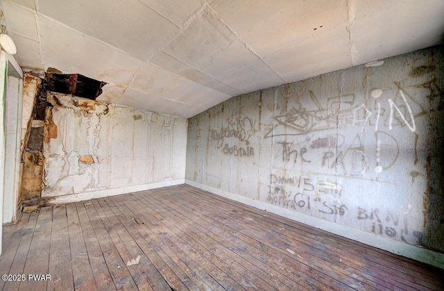 unfurnished room featuring hardwood / wood-style flooring and lofted ceiling