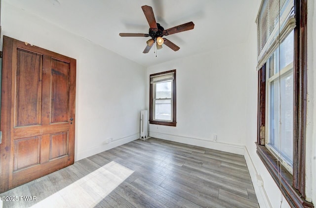 unfurnished room featuring radiator heating unit, light hardwood / wood-style floors, and ceiling fan