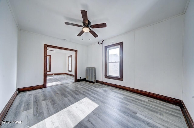 empty room with crown molding, radiator, ceiling fan, and light hardwood / wood-style floors