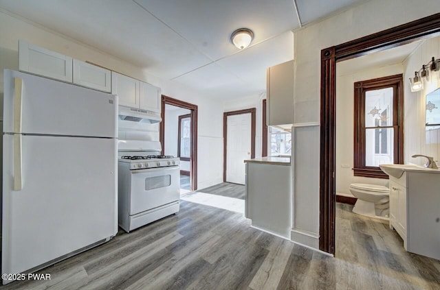 kitchen with white cabinetry, sink, white appliances, and light hardwood / wood-style flooring