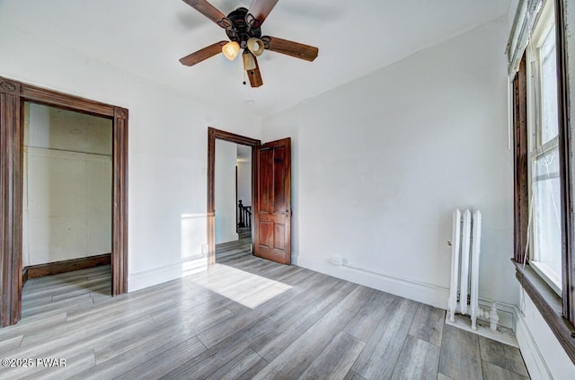 unfurnished bedroom featuring ceiling fan, radiator heating unit, and light hardwood / wood-style floors