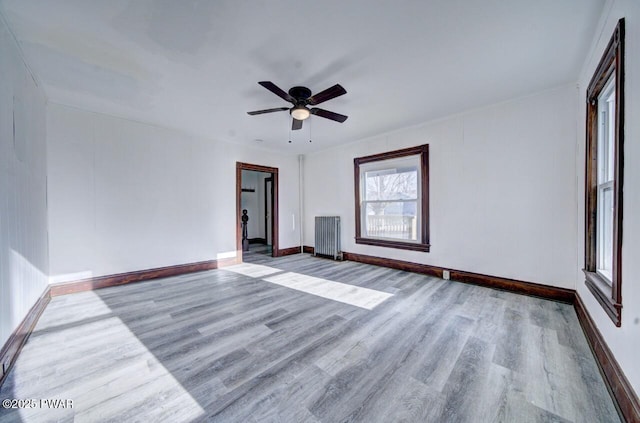 spare room featuring ceiling fan, radiator heating unit, and light hardwood / wood-style flooring