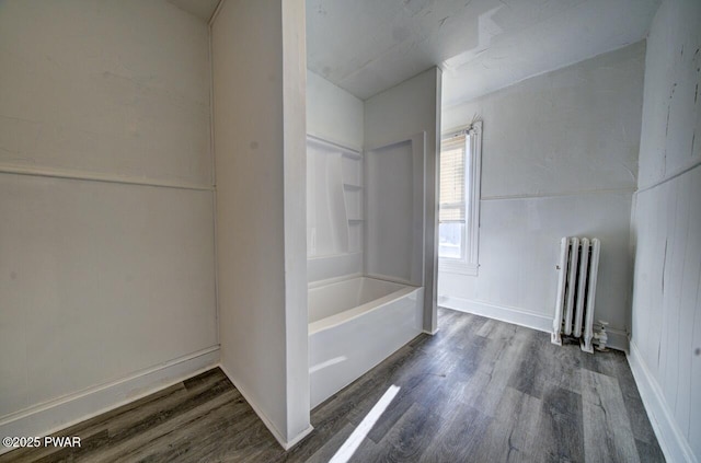 bathroom featuring radiator heating unit, bathtub / shower combination, and wood-type flooring