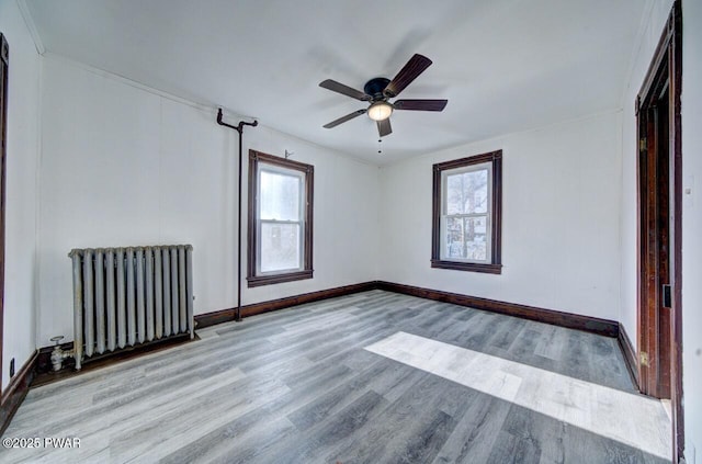 unfurnished room with radiator, ceiling fan, and light wood-type flooring