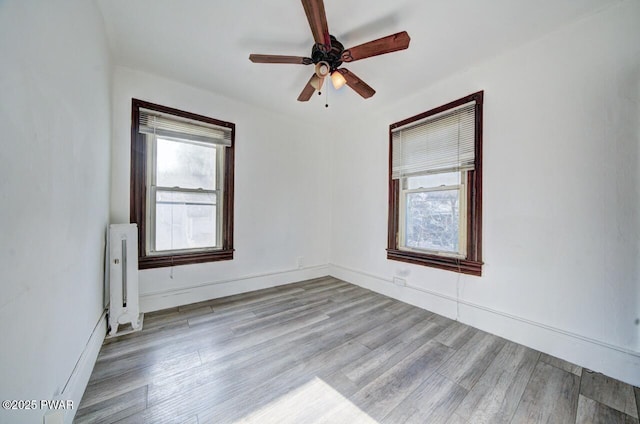 empty room with ceiling fan, radiator heating unit, and light wood-type flooring