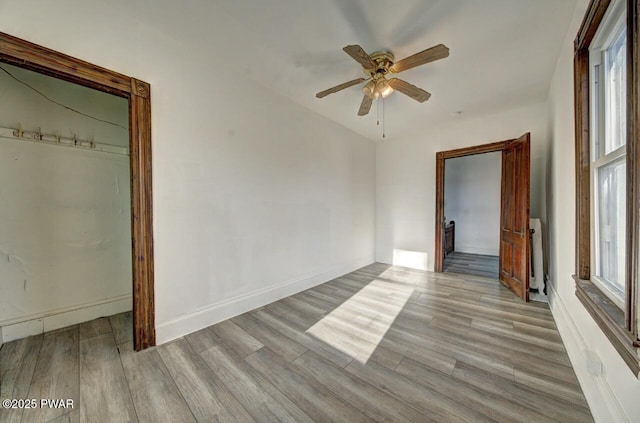 unfurnished bedroom featuring radiator, ceiling fan, and light wood-type flooring