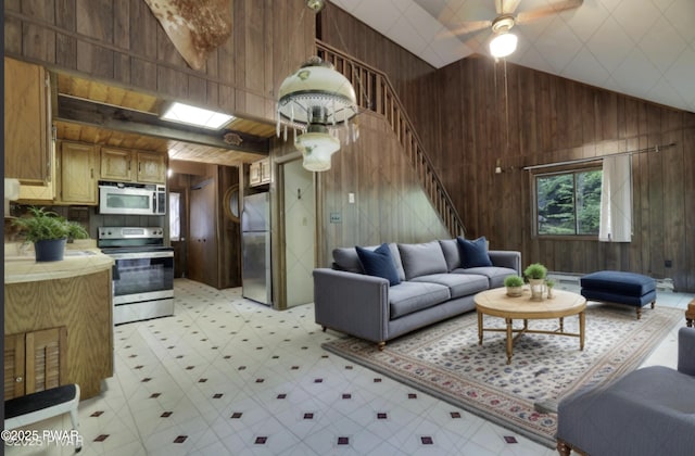 1086 Hampstead Rd, Bushkill, PA 18324 - living room with wood walls, light flooring, stairway, a ceiling fan, and high vaulted ceiling