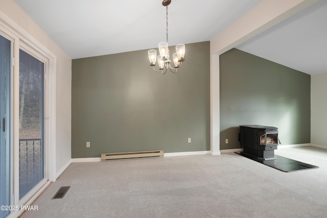 empty room featuring vaulted ceiling, a wood stove, carpet, a notable chandelier, and baseboard heating