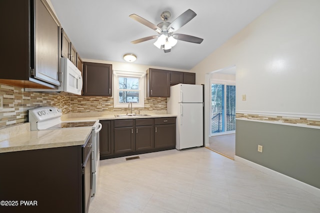 kitchen featuring dark brown cabinetry, sink, and white appliances