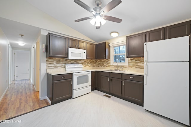 kitchen with white appliances, lofted ceiling, sink, and backsplash