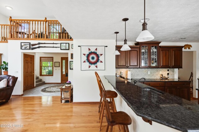 119 Canoebrook Dr, Hawley, PA 18428 - kitchen with a sink, a kitchen breakfast bar, glass insert cabinets, tasteful backsplash, and dark stone counters