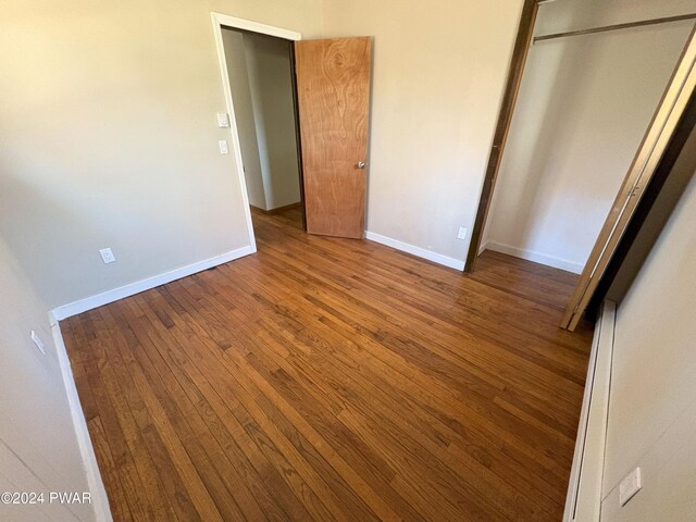 unfurnished bedroom with hardwood / wood-style flooring and a closet