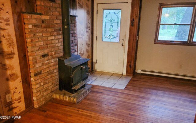 foyer entrance featuring light hardwood / wood-style floors, a wood stove, and a baseboard heating unit