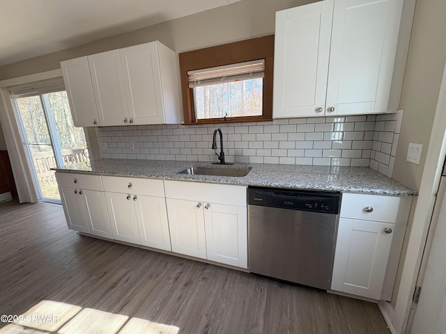 kitchen with light stone countertops, white cabinetry, sink, tasteful backsplash, and stainless steel dishwasher