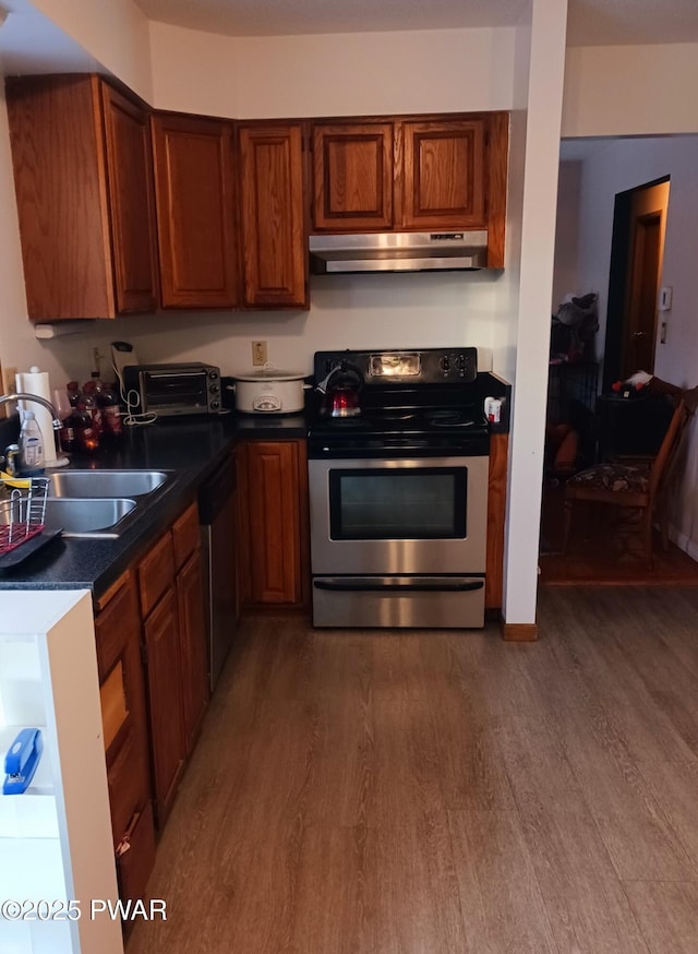 kitchen featuring appliances with stainless steel finishes, brown cabinets, a sink, and under cabinet range hood