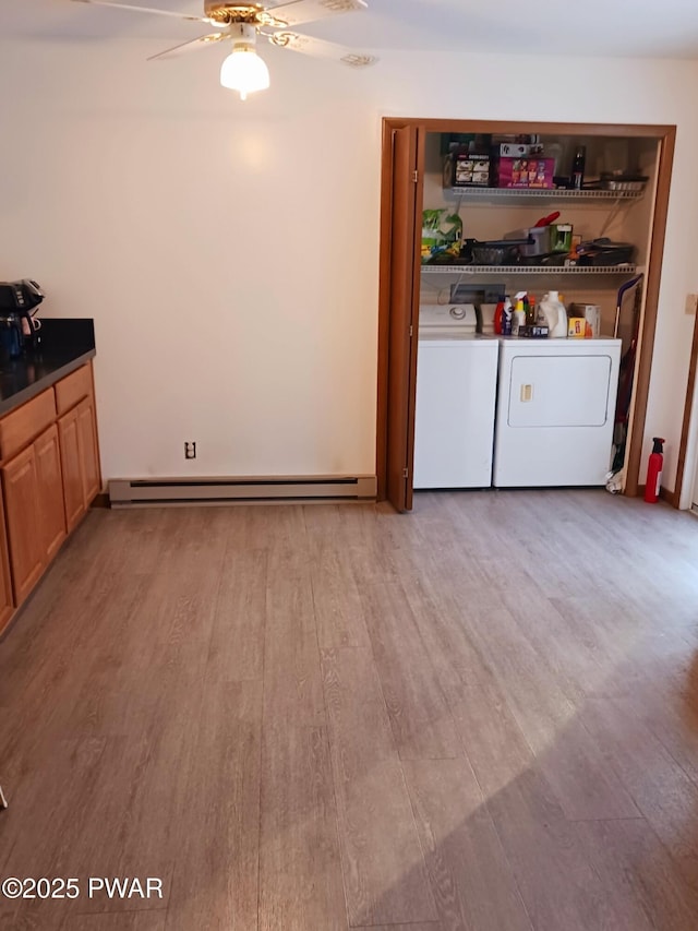 laundry room featuring light wood-style flooring, baseboard heating, a ceiling fan, separate washer and dryer, and laundry area