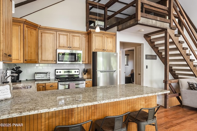 1749 Rockpoint Ct, Lake Ariel, PA 18436 - kitchen featuring stainless steel appliances, a sink, a peninsula, a breakfast bar area, and a high ceiling