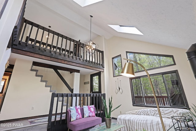 living room with baseboards, high vaulted ceiling, wood finished floors, and a skylight