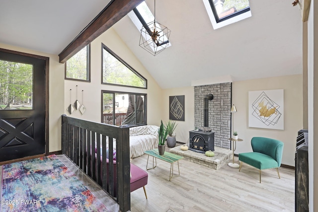 bedroom with a skylight, a wood stove, wood finished floors, high vaulted ceiling, and beamed ceiling