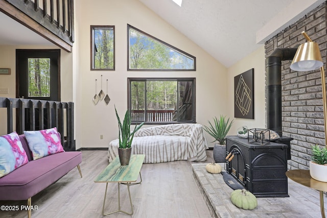 living room with high vaulted ceiling, wood finished floors, and a wood stove
