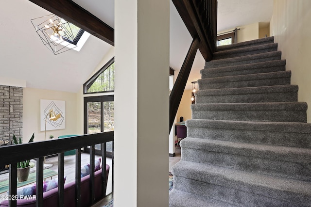 stairway featuring beam ceiling, a skylight, and high vaulted ceiling