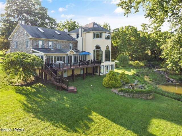 back of property with a lawn and a wooden deck