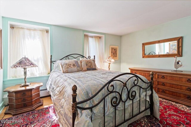 bedroom featuring light wood-type flooring and a baseboard heating unit