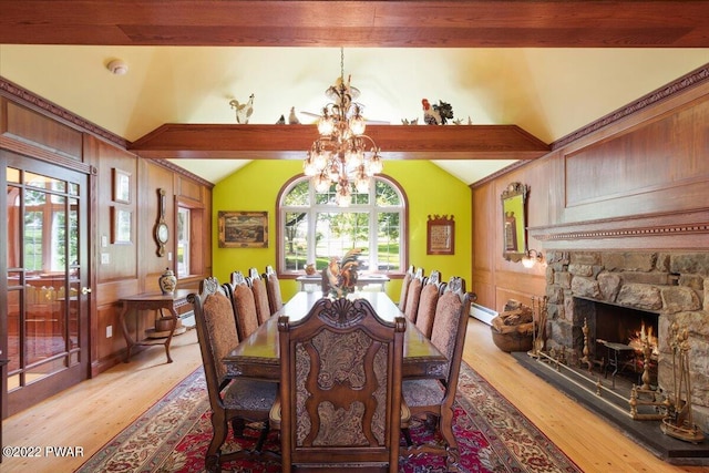 dining space with a fireplace, vaulted ceiling with beams, light hardwood / wood-style flooring, and an inviting chandelier