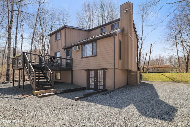rear view of house with a wall unit AC, a chimney, french doors, a wooden deck, and stairs