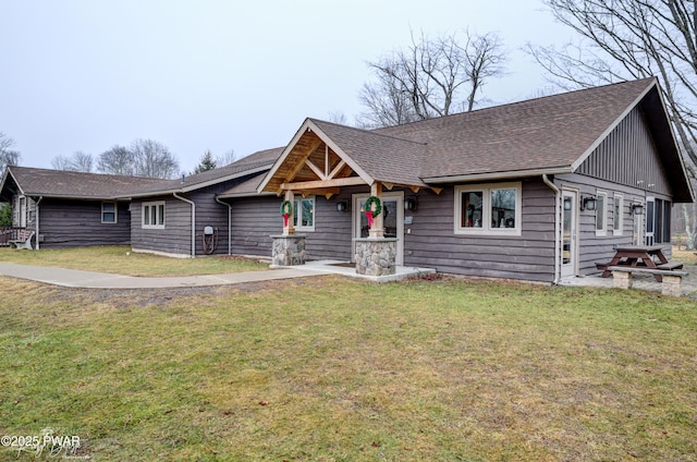view of front facade featuring roof with shingles and a front yard