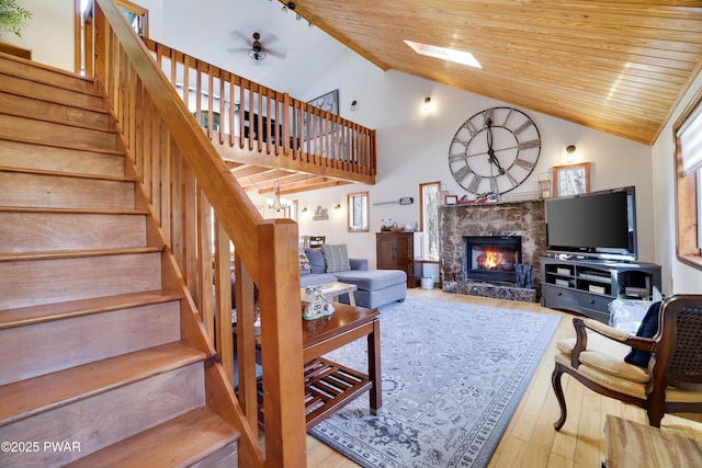 living area with a fireplace, stairs, a ceiling fan, wooden ceiling, and wood finished floors