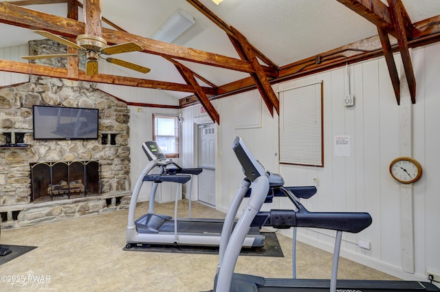 workout room with a ceiling fan, baseboards, vaulted ceiling, and a fireplace