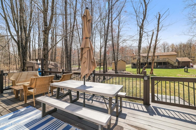deck with a storage shed, a yard, outdoor dining space, and an outbuilding
